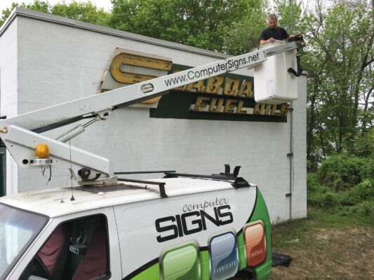 A Man on a Crane Installing Sign Board