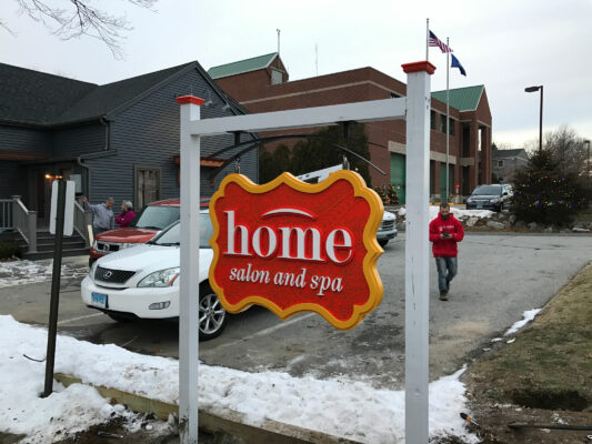 A Home Salon and Spa Sign on a White Post