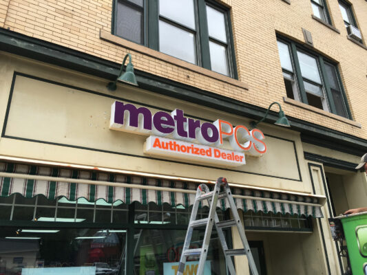 A Metro PCS Sign Being Installed on a Building