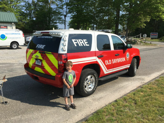 A Small Boy Standing Beside a Fire Car