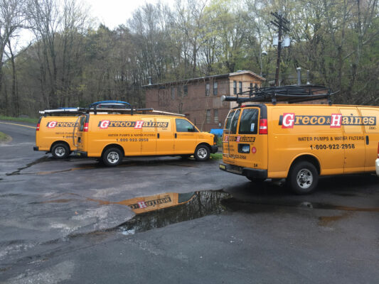 A Group of Yellow Color Vans With Greco Haines Logo