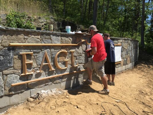 Two Men Walking on a Sign Board on a Sign Wall