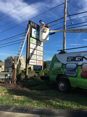 Two Men on a Crane Fixing a Sign Post