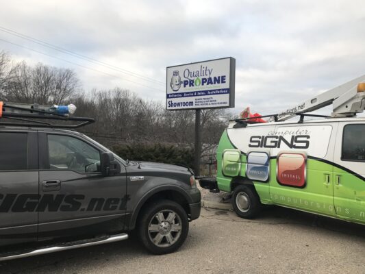 A Sign Company Vehicle Standing by a Board